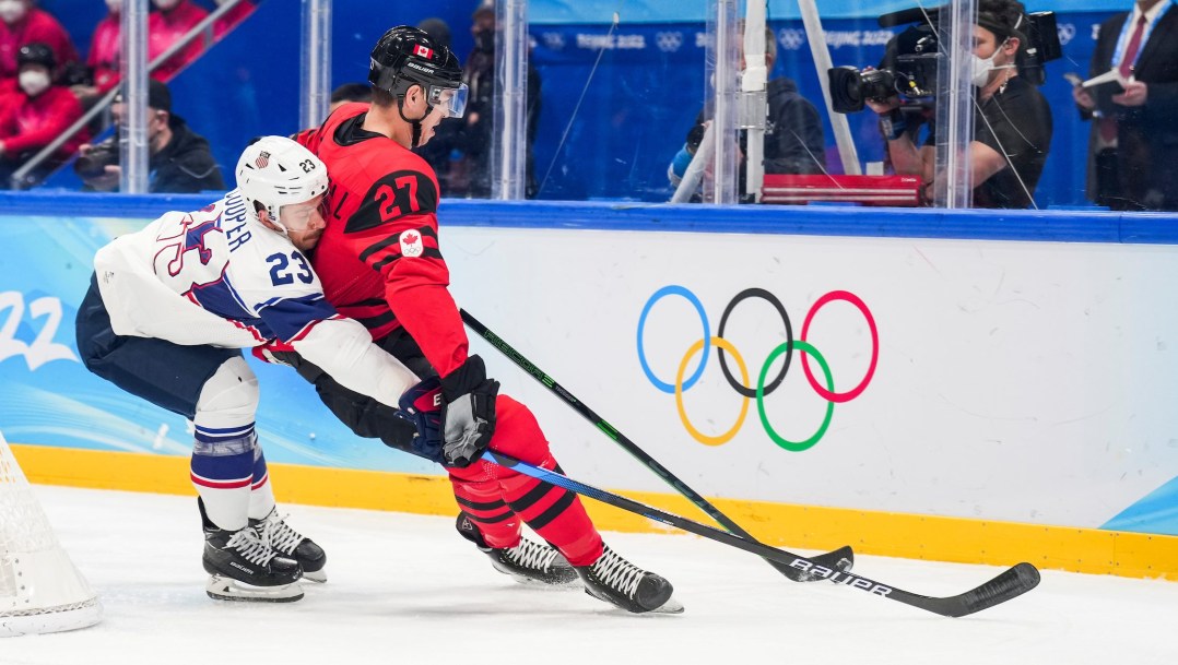 Adam Cracknell and an American player battle for the puck by the boards
