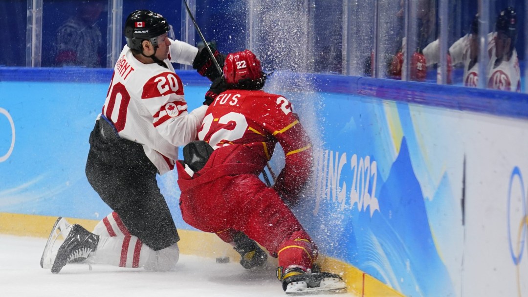 Alex Grant on his knees by the boards as he battles for the puck with a Chinese player