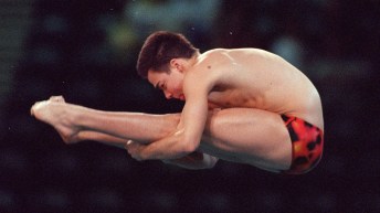 Alex Despatie in a red diving trunks performs a dive in pike position