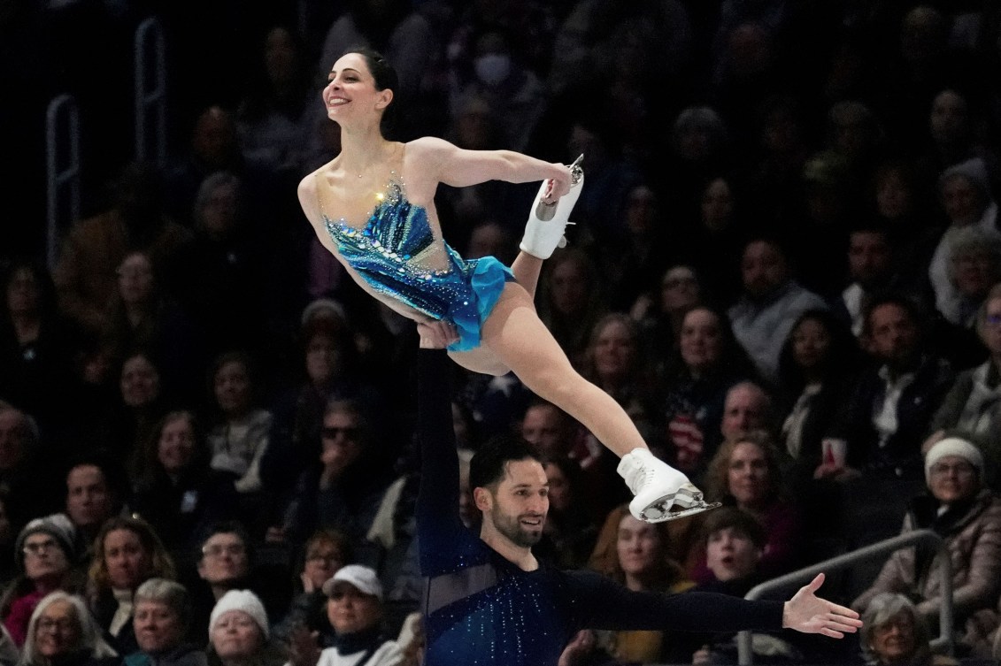 Deanna Stellato-Dudek in a multi tone blue dress is in a lift above her partner's head