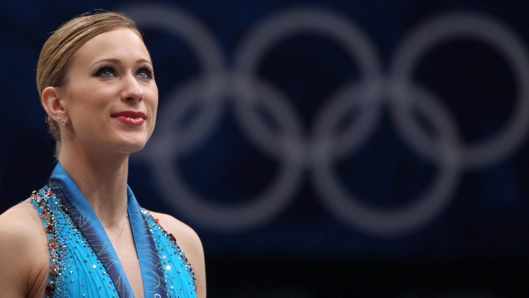 Joannie Rochette looks wistfully to the sky with the Olympic rings behind her
