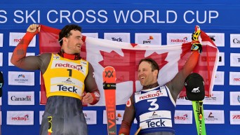 Reece Howden and Kevin Drury hold a Canadian flag between them on the podium
