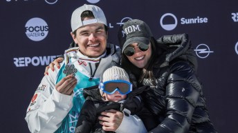 Mikael Kingsbury poses with his silver medal and his baby son on the podium at the world championships