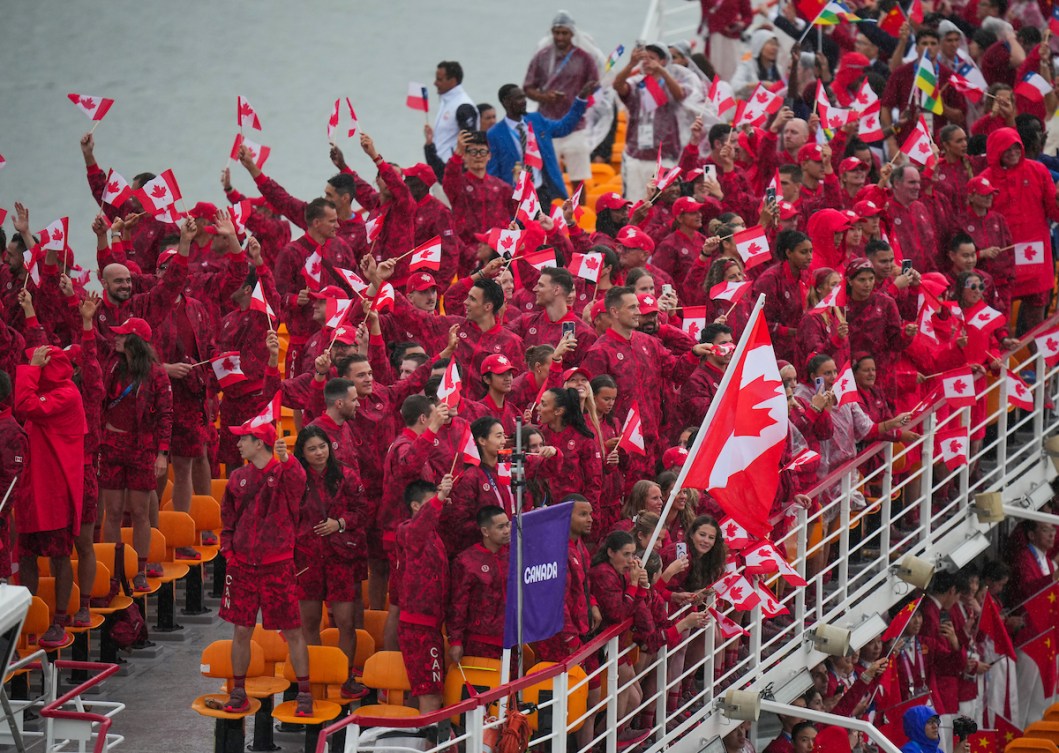Team Canada athletes all dressed in red on the top deck of a boat during the Paris 2024 Opening Ceremony