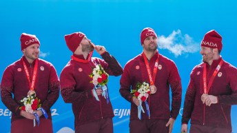 Ryan Sommer kisses his bronze medal as his teammates look on