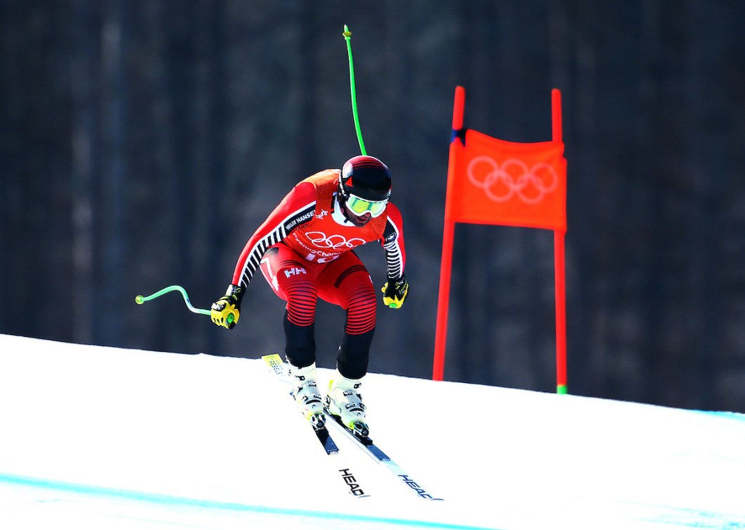 Manny Osborne-Paradis in a red ski suit skis past a red gate