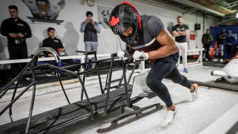 Yohan Eskrick-Parkinson practices pushing a bobsleigh while wearing a helmet
